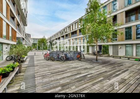 Biciclette parcheggiate vicino alla recinzione in cortile tra moderni edifici residenziali sotto il cielo blu durante il giorno Foto Stock