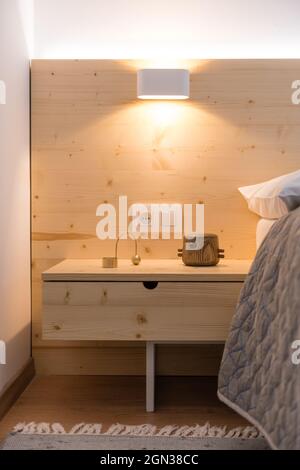Tavolo in legno accanto al letto in camera da letto di appartamento moderno Foto Stock