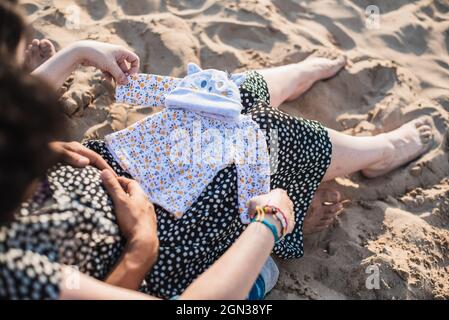 Set di vestiti per bambini sul grembo di una coppia in attesa. Foto Stock
