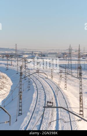 Vista con drone del treno sulla ferrovia su terreno nevoso sotto il cielo blu chiaro Foto Stock