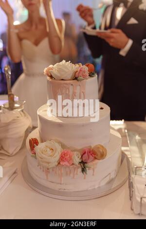 Torta nuziale sposi novelli in festa, decorato con rose dolci. Concetto di piccola impresa, torte da forno e dolci per eventi. Persone irriconoscibili. Foto Stock