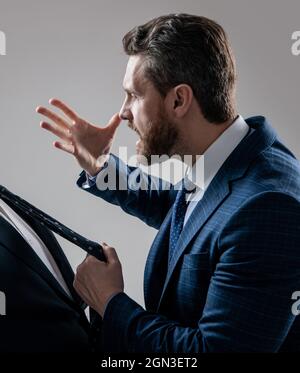 Aggressivo avvocato in tuta fare minacciare gesto tirando uomo cravatta sfondo grigio, minaccioso Foto Stock