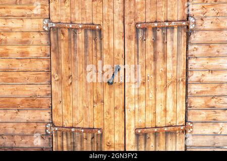 Tradizionale cancello di legno vecchio con cardini di metallo voluminosi Foto Stock