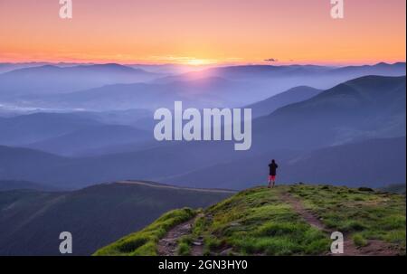 Uomo da solo sulla cima della montagna che guarda sulla valle della montagna nella nebbia Foto Stock