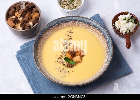 Zuppa vegetariana sana di panna a base di verdure, zuppa di purea di zucca in un piatto su sfondo bianco, primo piano. Foto Stock