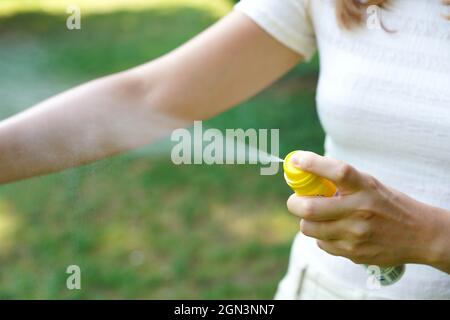 Giovane donna che applica repellente zanzara sul suo braccio durante l'escursione in natura. Repellente per insetti. Protezione della pelle contro il segno di spunta e l'altro insetto. Concentratevi su Th Foto Stock