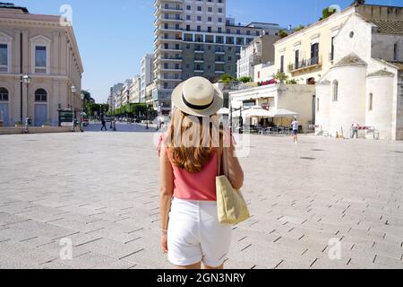 Bella giovane donna alla moda che cammina in piazza del Ferrarese a Bari Foto Stock