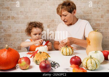 buona nipote di famiglia con nonna che fa zucca di halloween a casa Foto Stock