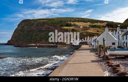 PENNAN ABERDEENSHIRE SCOZIA LE SCOGLIERE ROSSE IL MARE DELLA BAIA E LA FILA DI CASE Foto Stock