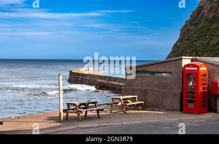 PENNAN VILLAGE ABERDEENSHIRE SCOTLAND THE RED TELEPHONE BOX THE BAY SEA AND HARBOR WALL Foto Stock