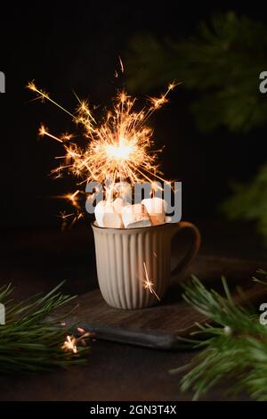 Caffè di Natale o cacao con marshmallow e scintillanti su tavolo festivo scuro e rami sempreverdi. Riscaldamento della bevanda. Vacanze natalizie. Primo piano. Vert Foto Stock