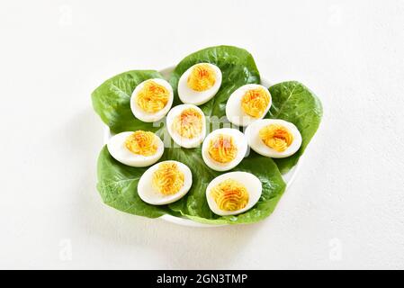 Uova sgusciate con paprika, senape e maionese. Appettizzatore per colazione o pranzo. Sfondo bianco, vista ravvicinata Foto Stock