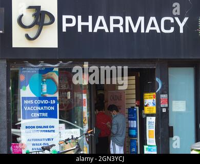 Un poster del centro di vaccinazione Covid-19 dell'NHS (National Health Service) è visto all'esterno di una farmacia a Londra. Foto Stock