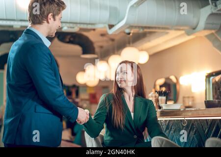 Uomo e donna che scuotono le mani in un caffè Foto Stock