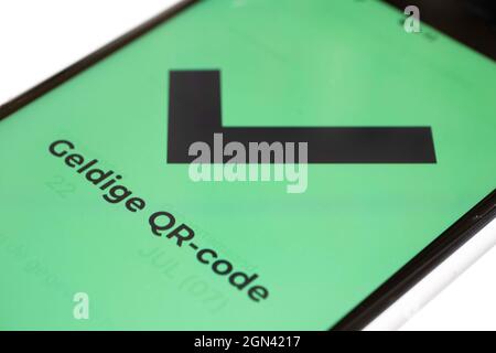 Il testo olandese "codice QR valido" sullo schermo verde di uno smartphone indica che il visitatore è stato vaccinato o è stato provato negativo. Isolato su bianco Foto Stock