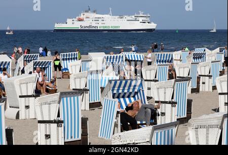 Meclemburgo-Pomerania occidentale, 22 settembre 2021, 22 settembre 2021, Meclemburgo-Pomerania occidentale, Warnemünde: I visitatori godono del sole sul Mar Baltico mentre arriva un traghetto Scandlines. Il tempo soleggiato ha sostituito le nuvole e la pioggia. Foto: Bernd Wüstneck/dpa-Zentralbild/dpa Foto Stock