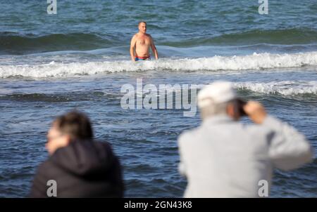 22 settembre 2021, Meclemburgo-Pomerania occidentale, Warnemünde: I visitatori possono godersi il sole sul Mar Baltico mentre arriva un traghetto Scandlines. Il tempo soleggiato ha sostituito le nuvole e la pioggia. Foto: Bernd Wüstneck/dpa-Zentralbild/dpa Foto Stock