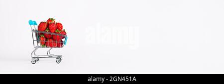 Carrello giocattolo o carrello pieno di grandi fragole rosse mature isolate su sfondo bianco. Concetto di vendita del raccolto di Berry. Striscione lungo con spazio per la copia Foto Stock