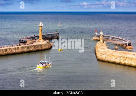 Piccole barche a motore utilizzate per viaggi turistici che entrano e lasciano il porto di Whitby nel Mare del Nord, Whitby, Redcar e Cleveland distretto, yorks del Nord Foto Stock