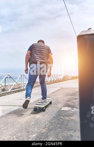 Il modo perfetto per attraversare queste strade, adolescente in abiti da strada si alza con una tavola lunga, guarda la macchina fotografica e sorride. Cultura di strada. Foto Stock