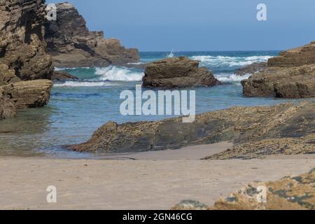 Onde di mare che si lavano su rocce che sporgono dall'acqua alla spiaggia di As Catedrais in Spagna Foto Stock