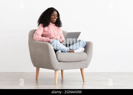 Donna afro-americana libera positiva che lavora da casa Foto Stock
