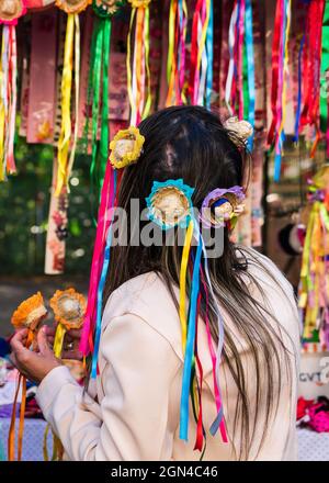 Donna arrangiando mini cappelli con nastri in vendita alla fiera Belo Horizonte Hippie in Brasile. Questi ornamenti per capelli sono per la Festa Junina, un Brasile. Foto Stock