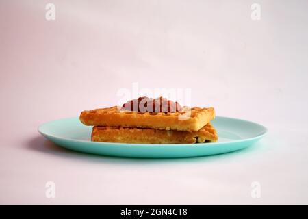 Waffle belgi con marmellata di albicocche su piatto turchese Foto Stock