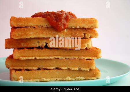 Waffle belgi con marmellata di albicocche su piatto turchese Foto Stock