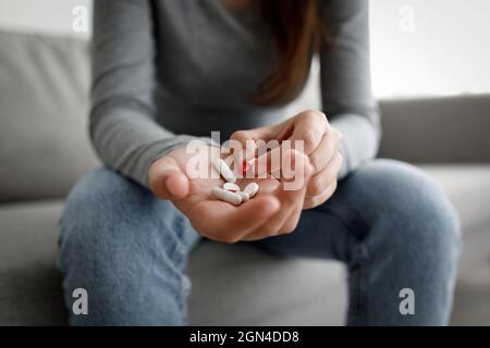 Irriconoscibile infelice depressa millenaria femmina caucasica mette le pillole dal vaso a portata di mano per suicidio commettere Foto Stock