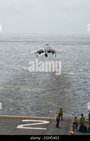 Mar Arabico, in mare. 11 Settembre 2021. I marinai della Marina degli Stati Uniti guardano come un velivolo da caccia Marine Corps AV-8B Harrier, attaccato al Marine Attack Squadron 214, esegue un decollo verticale dal ponte di volo della nave da assalto anfibio di classe Wasp USS Essex 10 settembre 2021 nel Mare Arabico. Credit: MC3 Isaak Martinez/U.S. Navy/Alamy Live News Foto Stock