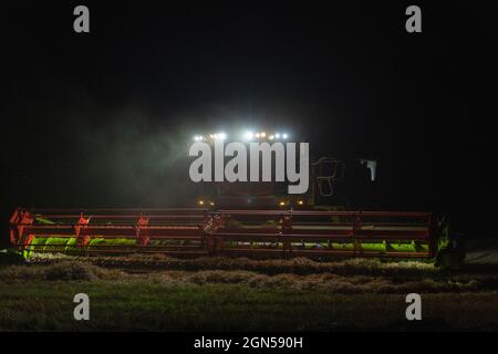 Una mietitrebbia che lavora da tardi fino alla sera in una fattoria scozzese Foto Stock