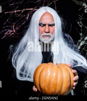 Bell'uomo di Halloween con zucca in mano. Uomo diavolo. Maschio in costume da strega pronto per la festa di Halloween. Foto Stock
