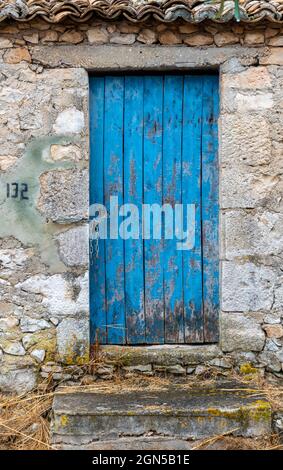 vecchia porta dipinta di legno, porta cottage dipinta di blu, porta rustica maltempo battuta, verniciatura afflitta, elegante porta fienile greco, tipicamente greco. Foto Stock