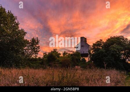 Royston, Barnsley, South Yorkshire, Regno Unito, 22 settembre 2021, Meteo. Formazioni di nubi illuminate al tramonto sul Rabbit Ings Country Park e i resti di Monckton Colliery dell'epoca delle miniere di carbone della Gran Bretagna. L'incantesimo caldo e secco continua nella stagione autunnale. Credit: Paul Biggins/Alamy Live News Foto Stock