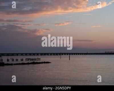 Ponte ferroviario e resti di molo e un molo a Bay St. Louis Mississippi con un cielo nuvoloso. Fotografato al crepuscolo. Foto Stock