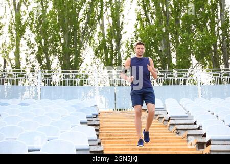 Giovane uomo sportivo che corre al piano inferiore allo stadio Foto Stock