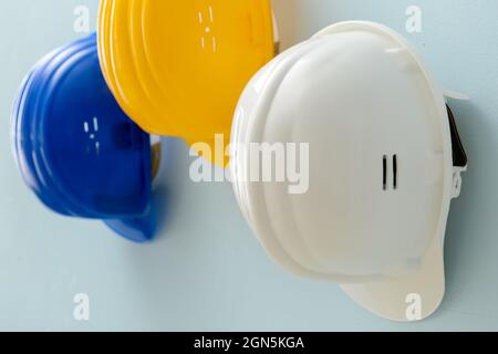 Gli hardhats in plastica appesi alla parete colorata Foto Stock