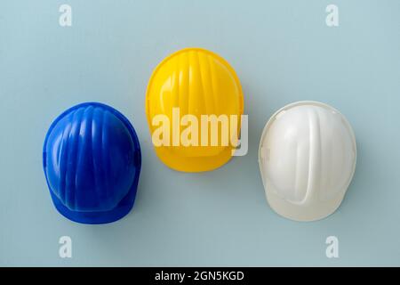 Gli hardhats in plastica appesi alla parete colorata Foto Stock