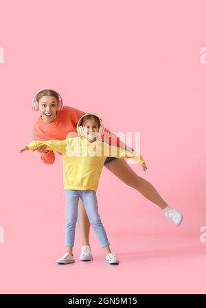 La giovane donna e la sua bambina ballano e ascoltano musica su sfondo colorato Foto Stock