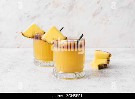 Bicchieri di cocktail mai tai e fette di ananas su un tavolo leggero Foto Stock