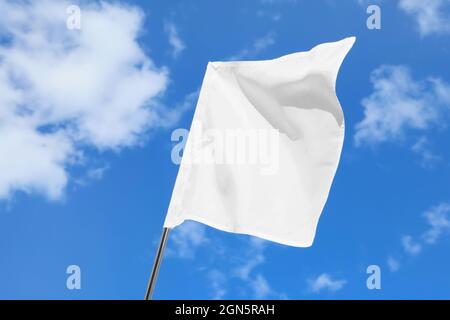 Bandiera bianca ondulata contro il cielo blu Foto Stock