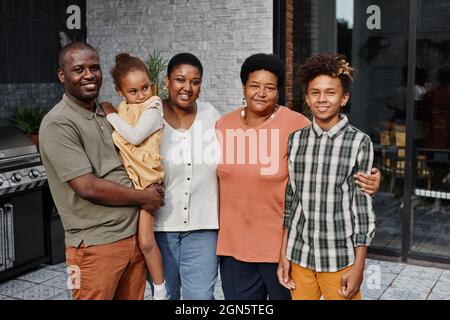 Ritratto di grande famiglia afroamericana guardando la macchina fotografica mentre si posa insieme in terrazza all'aperto e sorridendo felicemente Foto Stock