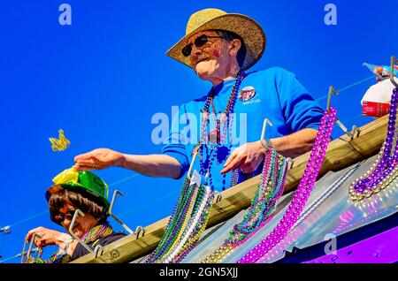 Un uomo lancia delle perle da un galleggiante del Mardi Gras durante la parata del Mardi Gras del giorno del Caino del Joe, 7 febbraio 2016, a Mobile, Alabama. Foto Stock