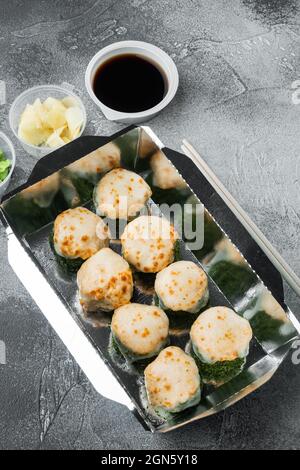 Take away sushi rotoli in contenitori, philadelphia rotoli e gamberi cotti set, su sfondo di pietra grigia Foto Stock