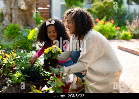 Felice afroamericana madre e figlia piantare fiori Foto Stock