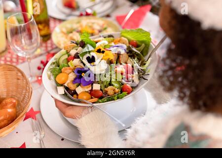 Mano di donna afroamericana che tiene ciotola con insalata Foto Stock