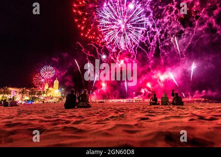 Sitges, Spagna. 22 settembre 2021. Gli spettatori si riuniscono in una spiaggia per seguire la tradizionale esposizione di fuochi d'artificio presso la chiesa 'San Bartolomeu' durante la 'Festa maggiore' di Sitges, 'Santa Tecla'. L'edizione della corona di quest'anno ha assunto una forma molto ridotta lasciando la spiaggia quasi vuota. Credit: Matthias Oesterle/Alamy Live News Foto Stock