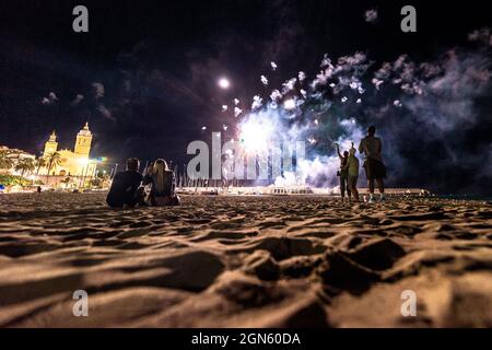 Sitges, Spagna. 22 settembre 2021. Gli spettatori si riuniscono in una spiaggia per seguire la tradizionale esposizione di fuochi d'artificio presso la chiesa 'San Bartolomeu' durante la 'Festa maggiore' di Sitges, 'Santa Tecla'. L'edizione della corona di quest'anno ha assunto una forma molto ridotta lasciando la spiaggia quasi vuota. Credit: Matthias Oesterle/Alamy Live News Foto Stock