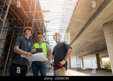 Team di lavoratori edili che discutono i dettagli del progetto con il supervisore esecutivo nel cantiere edile. Foto Stock
